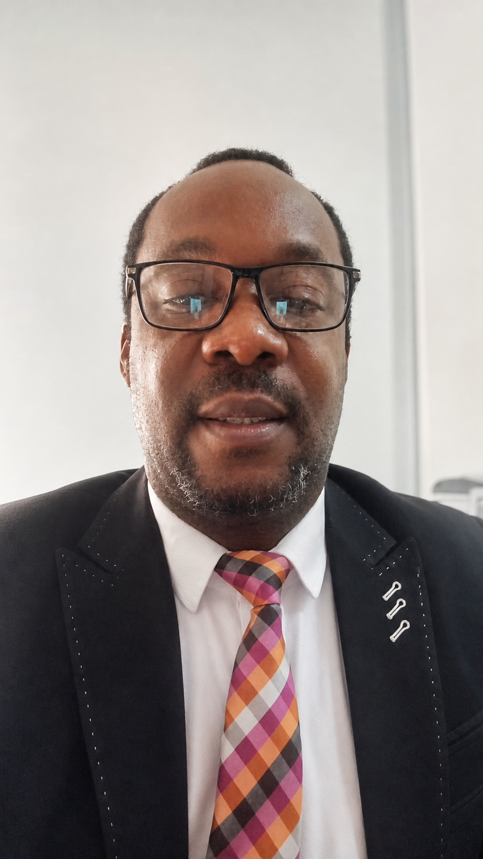 Dr. Prosper-Ohayagha Success in a dark suit and patterned tie